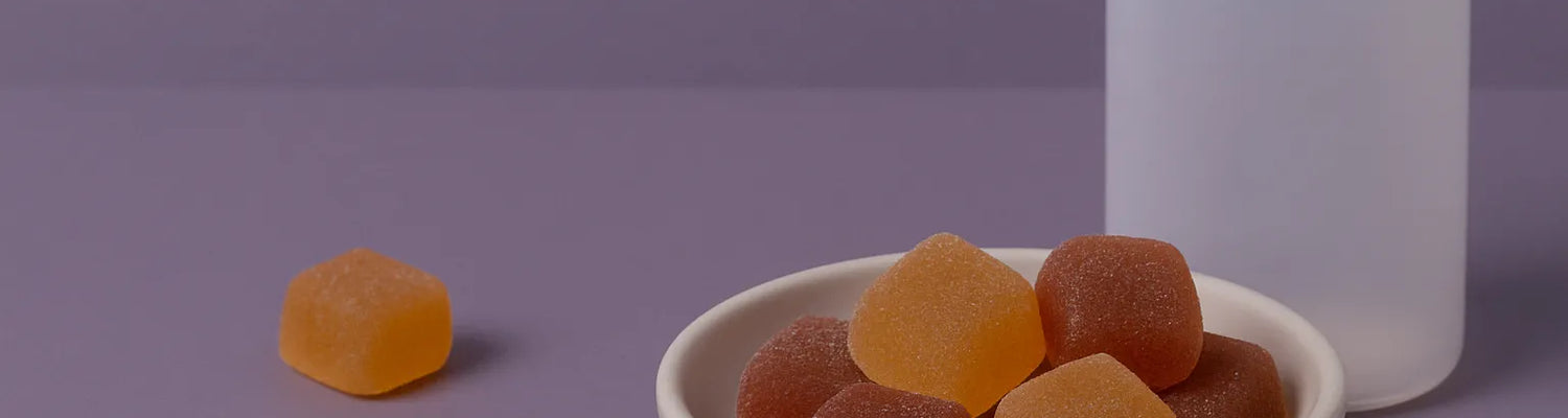 Gomas de melatonina com CBD e CBN numa taça com o frasco ao lado, sobre um fundo roxo